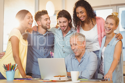 Business people looking at laptop in meeting room