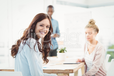 Portrait of smiling woman while sitting at desk