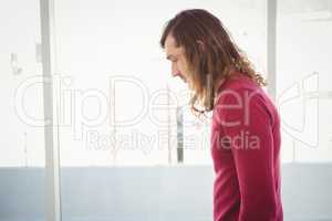 Serious man looking down while standing in office
