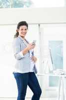 Portrait of confident pregnant businesswoman using phone
