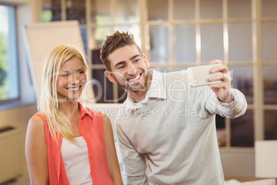 Businessman taking selfie with female colleague