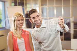 Businessman taking selfie with female colleague