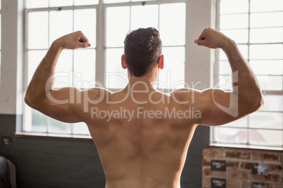 Rear view of muscular man flexing