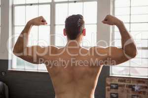 Rear view of muscular man flexing