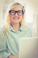 Portrait of smiling businesswoman with eyeglasses working on lap