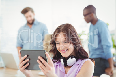 Smiling woman with headphones while using digital tablet