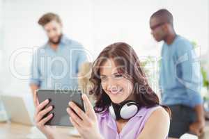 Smiling woman with headphones while using digital tablet