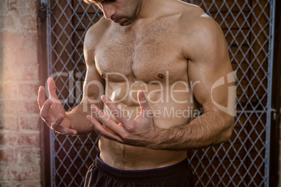 Midsection of shirtless man watching his hands