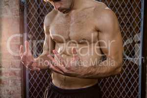 Midsection of shirtless man watching his hands