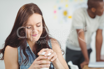 Smiling woman holding coffee cup while sitting at desk Smiling woman holding coffee cup while sitting at desk