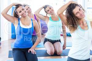 Cheerful women doing head exercise in fitness studio
