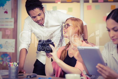 Colleagues holding camera with businesswoman using digital table