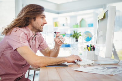 Hipster typing on keyboard while holding electronic cigarette