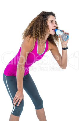 Young woman drinking water while bending