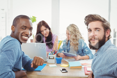 Portrait of smiling business people with women working on backgr