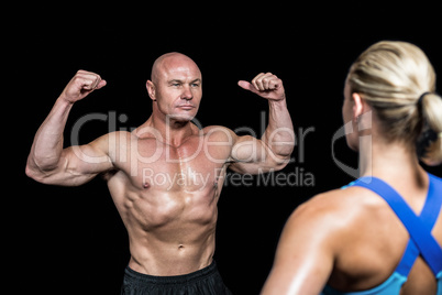 Bodybuilder flexing muscles in front of trainer