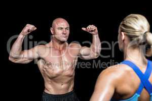 Bodybuilder flexing muscles in front of trainer