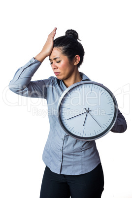 Woman slapping her forehead and holding a clock