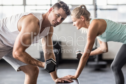 Couple exercising with dumbbells in gym