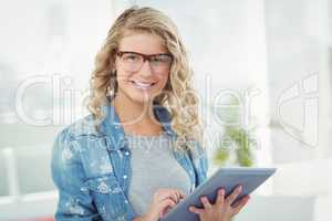 Portrait of smiling woman wearing eyeglasses while using digital