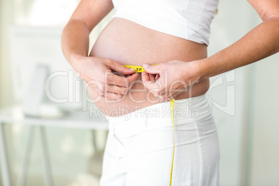 Midsection of woman measuring abdomen