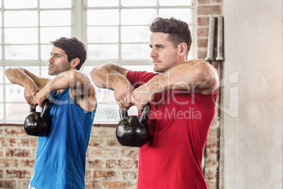 Muscular men lifting a kettle bell