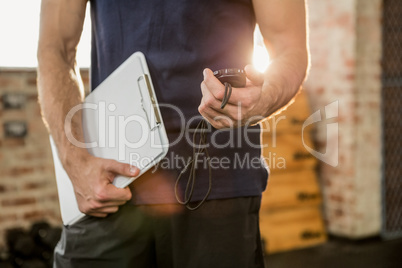 Midsection of trainer holding clipboard and stopwatch