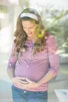 Happy pregnant woman standing by window