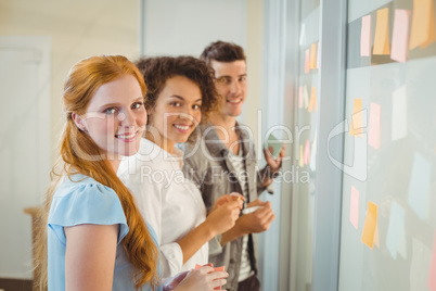 Portrait of smiling business people standing by glass wall