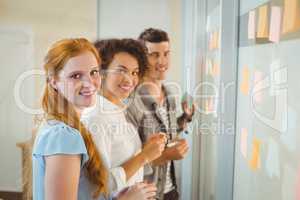 Portrait of smiling business people standing by glass wall