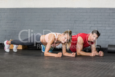 Fit couple planking together in gym