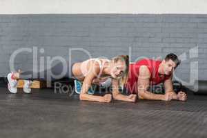 Fit couple planking together in gym