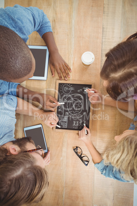 Close-up of people writing business terms on slate