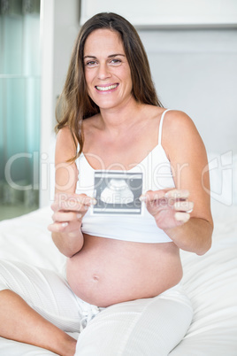 Portrait of happy woman showing sonogram