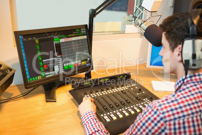 Radio host operating sound mixer while looking in monitor