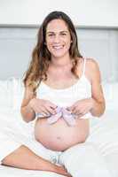 Portrait of happy woman with baby shoes on belly