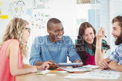 Happy business professionals using digital tablet at desk