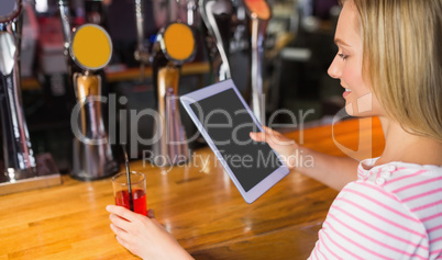Woman with drink holding digital tablet