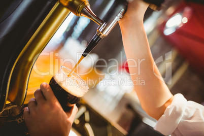 Cropped hand of barkeeper dispensing beer