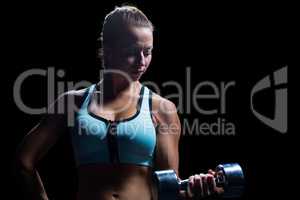 Fit woman concentrating while lifting dumbbell