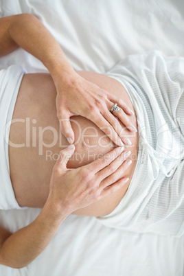 Overhead view of woman making heart on belly