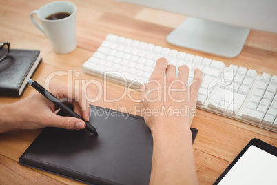 Hipster using graphics tablet on desk in office