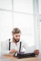 Hipster using typewriter at desk in office