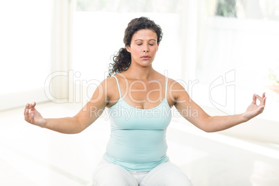 Pregnant woman sitting with eyes closed on exercise ball