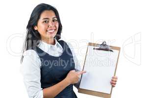 Woman smiling and pointing to her clipboard