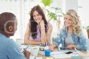 Smiling business people discussing while working at desk