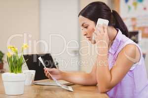 Businesswoman looking at document while talking on phone