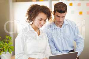 Business woman using digital tablet while male colleague