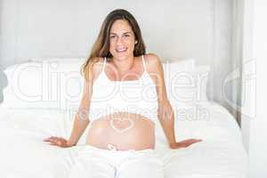 Portrait of woman with heart shape lotion on pregnant belly