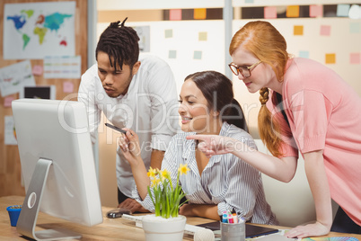 Smiling business people pointing towards computer in office